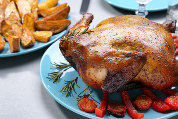 Plate with roasted beer can chicken on gray table