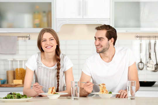 Young Couple Eating Pasta On Kitchen Table