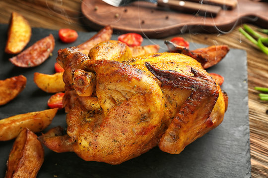 Slate plate with roasted beer can chicken on table, closeup