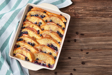 Baking dish with tasty bread pudding on wooden table