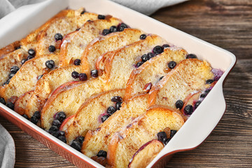Baking dish with tasty bread pudding on wooden table
