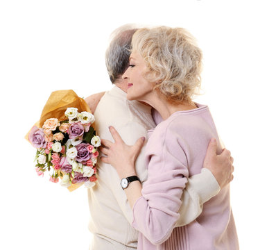 Happy senior couple with bouquet of flowers isolated on white