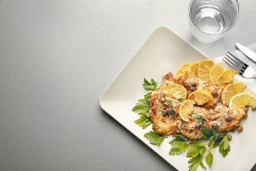 Plate with tasty Italian chicken piccata on table