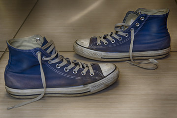 Old but whole blue sneakers with traces of road dust and dirt on the floor, hdr