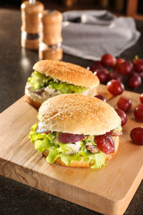 Wooden board with chicken salad in burger buns on table