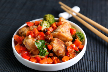 Chicken stir fry with vegetables and chopsticks on table