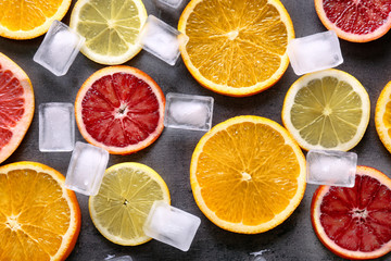 Juicy composition of citrus fruits and ice cubes on grunge background