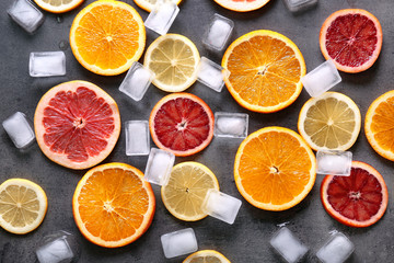 Juicy composition of citrus fruits and ice cubes on grunge background