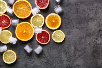 Juicy composition of citrus fruits and ice cubes on grunge background