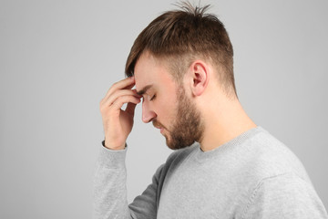 Fototapeta premium Young man suffering from headache on light background