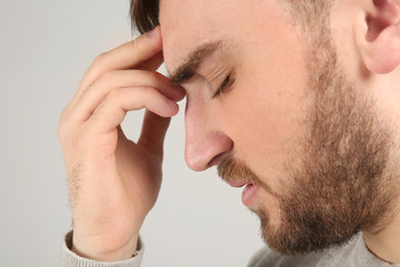 Obraz premium Young man suffering from headache on light background