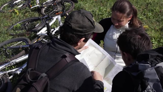 Group of tourists travelling by bicycles surching biking trail on map