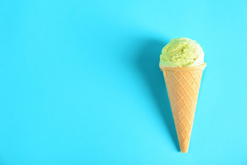 Delicious ice cream in waffle cone on color background
