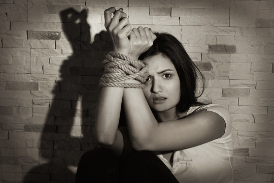Woman with tied hands on brick wall background