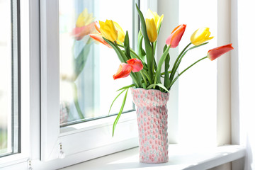 Vase with beautiful tulips on windowsill