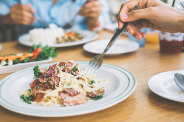 Selective focus. A hand of a woman eating spaghetti ham in coffee shop. Vintage photo.