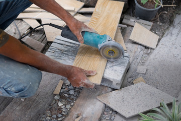 Worker using a hand circular saw to cut a tile