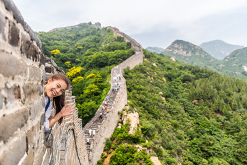 china travel tourist having fun waving hello at the Great Wall in Badaling smiling happy at camera. Woman tourist traveler enjoying her summer vacation holidays in Asia. Multicultural model.
