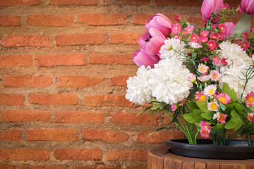 Artificial flowers and brick wall