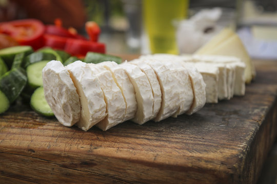 Sliced French goat cheese on wooden surface