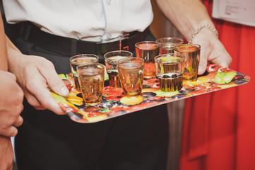 Glass of alcohol on a tray in his hands 7863.