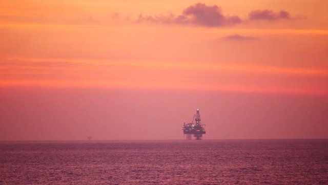 Jack up drilling rig in the middle of the ocean at sunrise time
