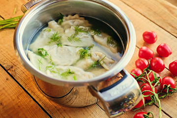 Boiled dumplings with parsley in a pot.