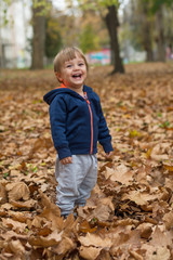 Happy little child, baby boy laughing and playing in autumn