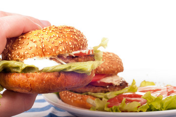 Hand holds fresh hamburger. Isolated on a white background
