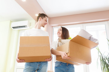 Happy young couple moving into new apartment with packaging boxes