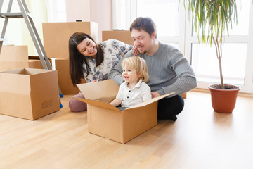 Happy young family with unpacking boxes at new home on moving day