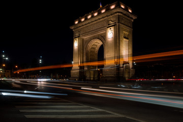 Traffic light trails on the background of the Arch of Triumph in Bucharest in the night
