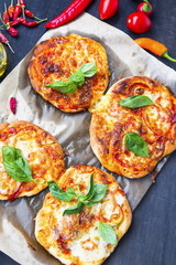 Mini pizzas or bruschettas with cheese, salami and fresh baby spinach leaves.Italian appetizers
