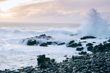 The high ocean waves bump against the rocks at sunset in the Canary Islands