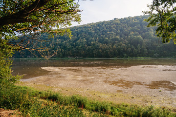A pile of stones on the bank of the Buller River, with the river in the background and the surrounding high cliffs covered in bush