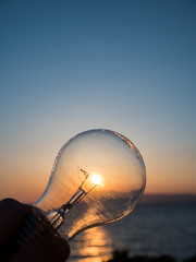 Man holding light bulb at sunset