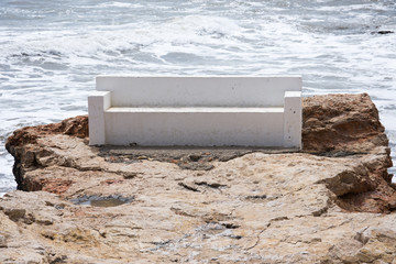 White bench of stone on the beach in the afternoon during a storm