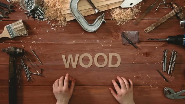 Top view time-lapse of a hand laying on wodden table word "WOOD"