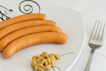 breakfast containing boiled sausage crenvursti with mustard on white plate