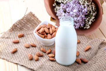 Fototapeta na wymiar Almond milk in glass bottle on wood background