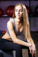 Fototapeta na wymiar Portrait of younf fitness girl with perfect skin and body sitting in gym