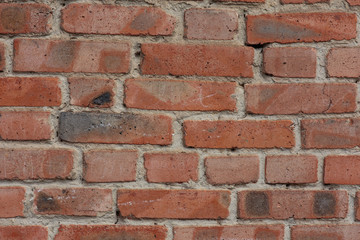 The texture of the background. An old wall of red cracked brick and cement with uneven masonry.