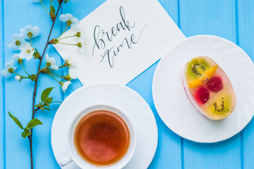 Still life with cup of tea and cake on the wooden background
