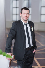 Handsome elegant groom in black wedding tuxedo with white shirt