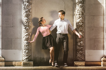 a man and a woman - swing dancers - posing near old concrete wall