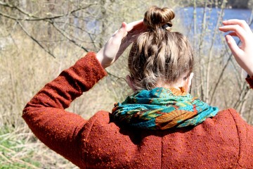 Beautiful picturesque young woman back side with old styled hairstyle on spring river background,...