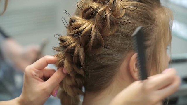 Portrait of a young woman in a beauty salon: creating a magnificent setting from curls. A blonde in a hairdresser does a beautiful hairstyle. Hair care and creating an image.