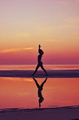 Silhouette young woman practicing yoga on the beach