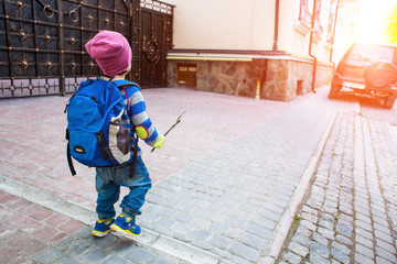 A boy with a backpack walking across the street.