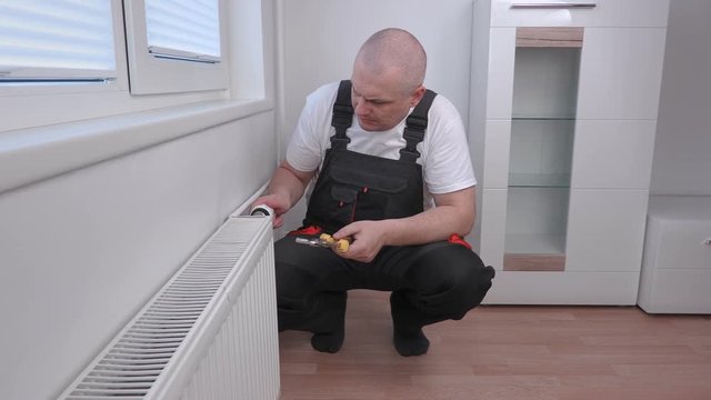 Plumber with wrench near radiator